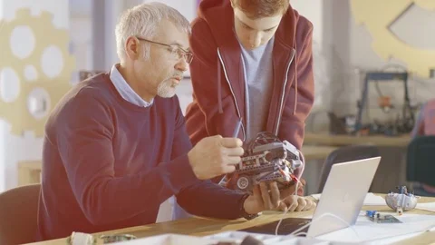 In Computer Science Class Teacher Examines programed Robot Engineered by Student Stock Footage 75784646
