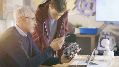 In Computer Science Class Teacher Examines programed Robot Engineered by Student Stock Footage 75784702