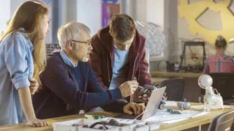 In Computer Science Class Teacher Examines programed Robot Made by Girl and B Stock Photos
