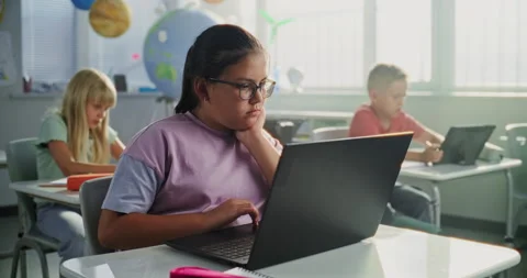Computer Science Lesson: Primary School Girl Sitting at Desk, Using Laptop in Stock Footage 317167045