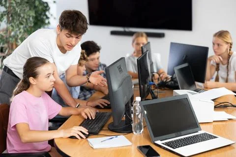 Computer science teacher helps young schoolgirl solve problem on computer Stock Photos