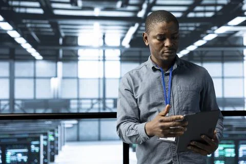 Computer scientist in data center uses tablet, verifying compliance of racks Foto stock
