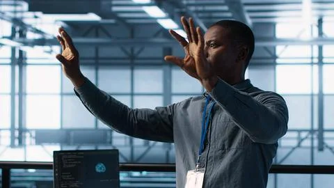 Computer scientist looking at holograms in data center, using AI Stock Photos