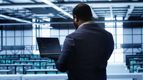 Computer scientist in server farm using laptop to patch network issues Stock Footage 277653881
