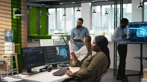Computer scientist in startup office reviewing AI system metrics Stock Footage 313017499