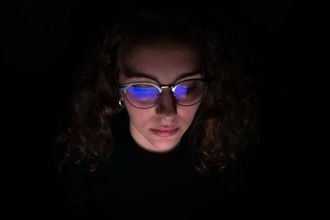 Computer screen reflected in the glasses of a woman who works at night. Overw Stock Photos