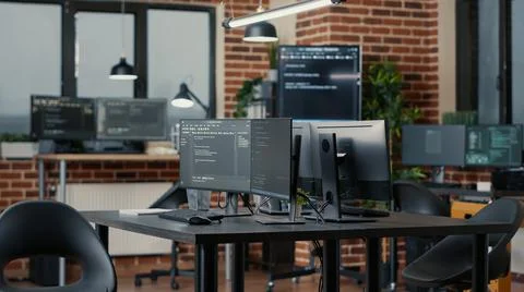 Computer screens running programming code in empty software developing agency Stockfoto's