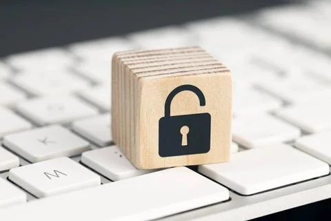 Computer security risk concept. Open padlock icon on wooden cube on comput... Stock Photos
