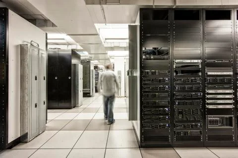 Computer server room racks with technician in background. Stock Photos