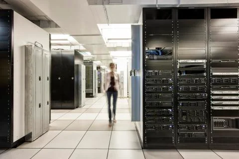 Computer server room racks with technician in background. Stock Photos