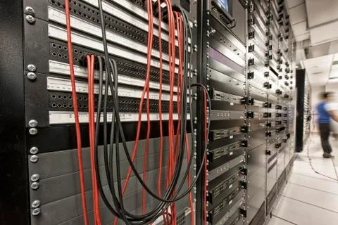 Computer server room racks with technician in background. Stock Photos