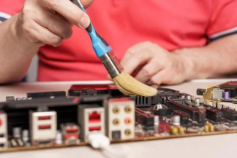 Computer service worker removes dust from motherboard Foto stock