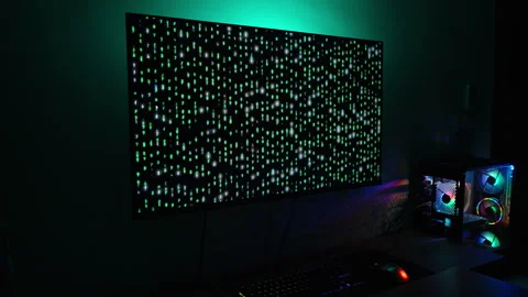 Computer Setup in a Dark Room, Displaying Green Matrix-Like Code on a Large Stock Footage 281459299