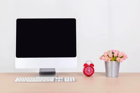 Computer showing blank screen  on work space table with red clock and flower Stock Photos