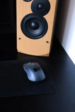 Computer speaker and mouse on a black desk with a mousepad Stock Photos
