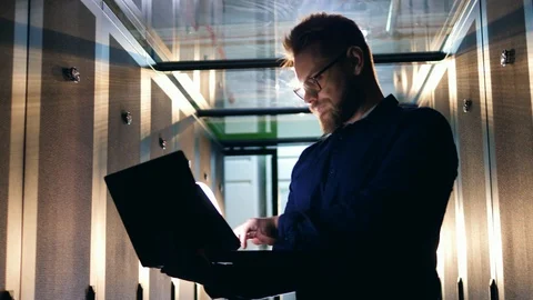 Computer system security specialist. A man stands in a server room, working with Video stock 111873332