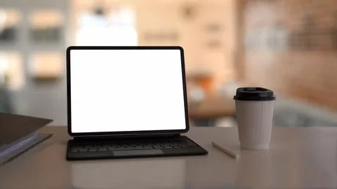 Computer tablet with blank display and coffee cup on white table. Stock Photos