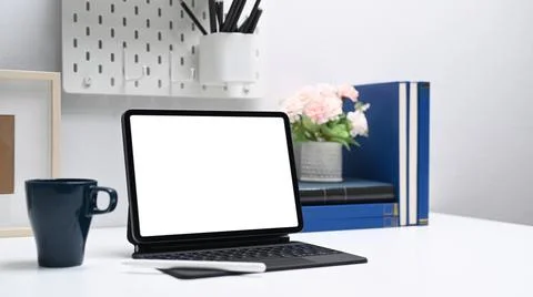 Computer tablet with empty screen, coffee cup and office supplies on white of Stock Photos