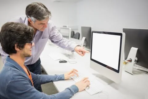 Computer teacher assisting a student Stock Photos
