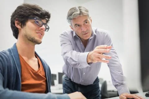 Computer teacher assisting a student Stock Photos