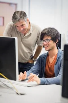 Computer teacher assisting a student Stock Photos