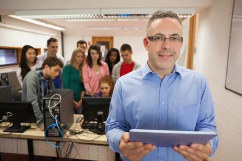 Computer teacher standing in front of his class using a tablet Fotos Stock