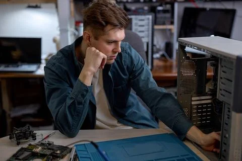 Computer technician checking a computer component after disassembling it Stock Photos