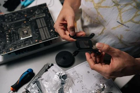 Computer technician mounting CPU cooler bracket on motherboard, ensuring precise Stock Photos