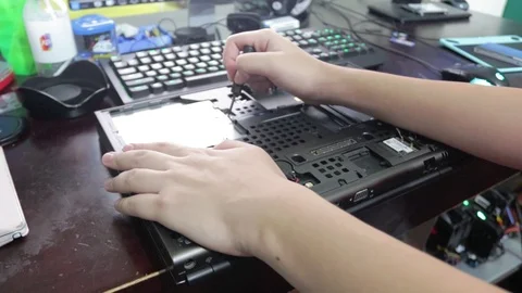 Computer technician remove a screw and a cd drive from a laptop Stock Footage 102192810