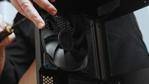 A computer technician unscrews a screw that secures a fan to a PC case. Assemble Stock Footage 300333820