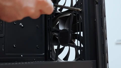 A computer technician unscrews a screw that secures a fan to a PC case. Assemble Stock Footage 300333878