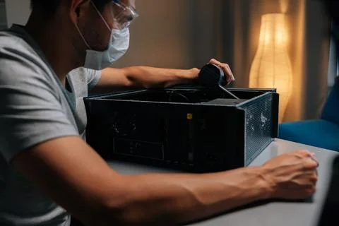 Computer technician wearing protective mask and safety eyewear cleaning desktop Stock Photos
