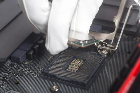 Computer technician wearing white gloves installing CPU into motherboard. Stock Photos