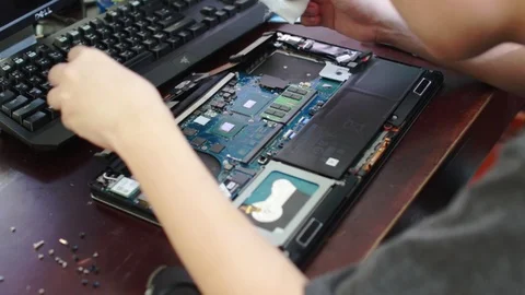 Computer technician wiping old thermal paste from CPU and heatsink in a laptop Stock Footage 102189290