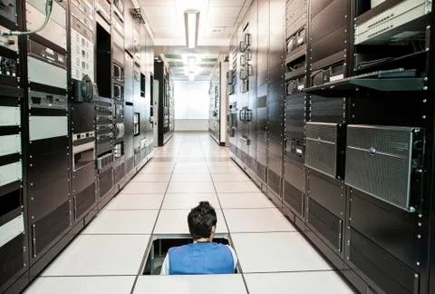 Computer technician working on wiring systems in the floor of a large computer Stock Photos