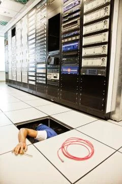 Computer technician working on wiring systems in the floor of a large computer Stock Photos