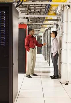 Computer technicians discussion an issue in a large computer server farm. Stock Photos