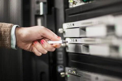 Computer techniican inserting thumb drive into a server in a server farm. Stock Photos