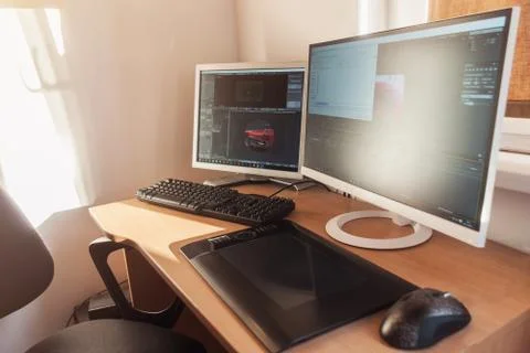 Computer with two big monitors and tablet in fron of bright window Stock Photos