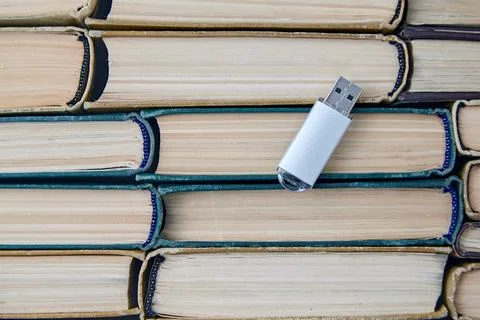 Computer usb drive on the background of a stack of old paper books. Information Stock Photos