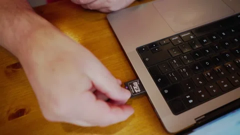 Computer user inserts digital data flash memory card into laptop slot Stock Footage 320392474