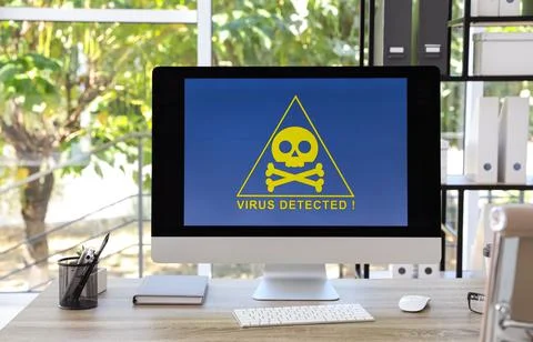 Computer with warning about virus attack on screen in office Stock Photos