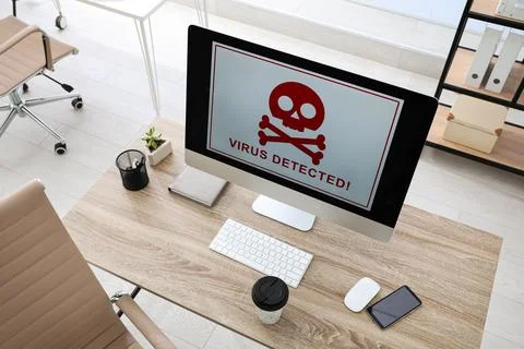 Computer with warning about virus attack on screen in office Foto stock