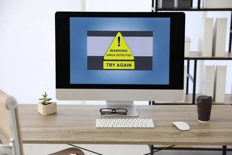 Computer with warning about virus attack on screen in office Foto stock