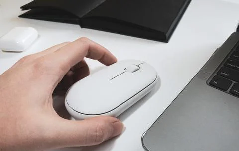 Computer white mouse in hand with notepad and laptop on a white background in Stock Photos