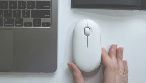 Computer white mouse in hand with notepad and laptop on a white background in Stock Photos