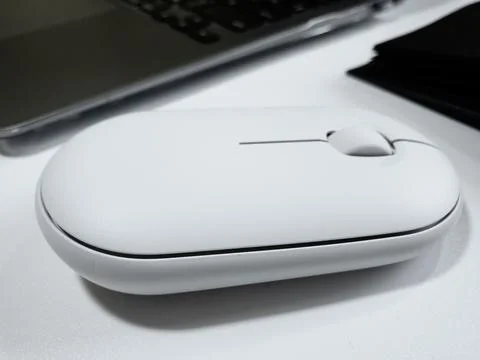 Computer white mouse in hand with notepad and laptop on a white background in Stock Photos