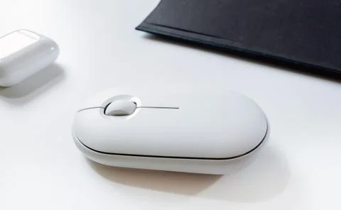 Computer white mouse in hand with notepad and laptop on a white background in Stock Photos