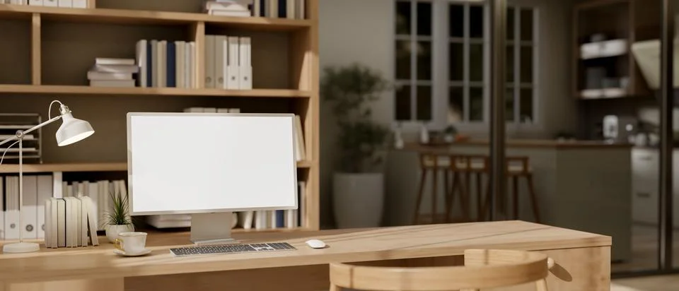 A computer with a white-screen mockup with decor are on a wooden desk in a .. Stock Photos