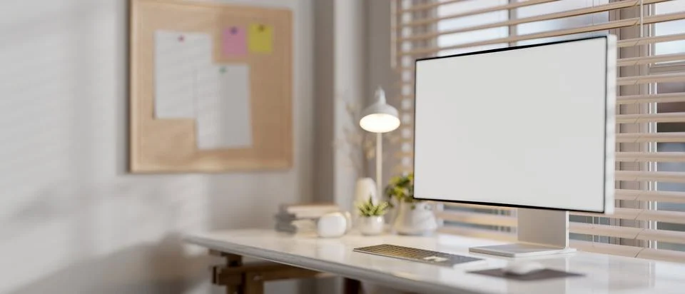 A computer with a white screen mockup on a desk against the window in a mod.. Stock Photos